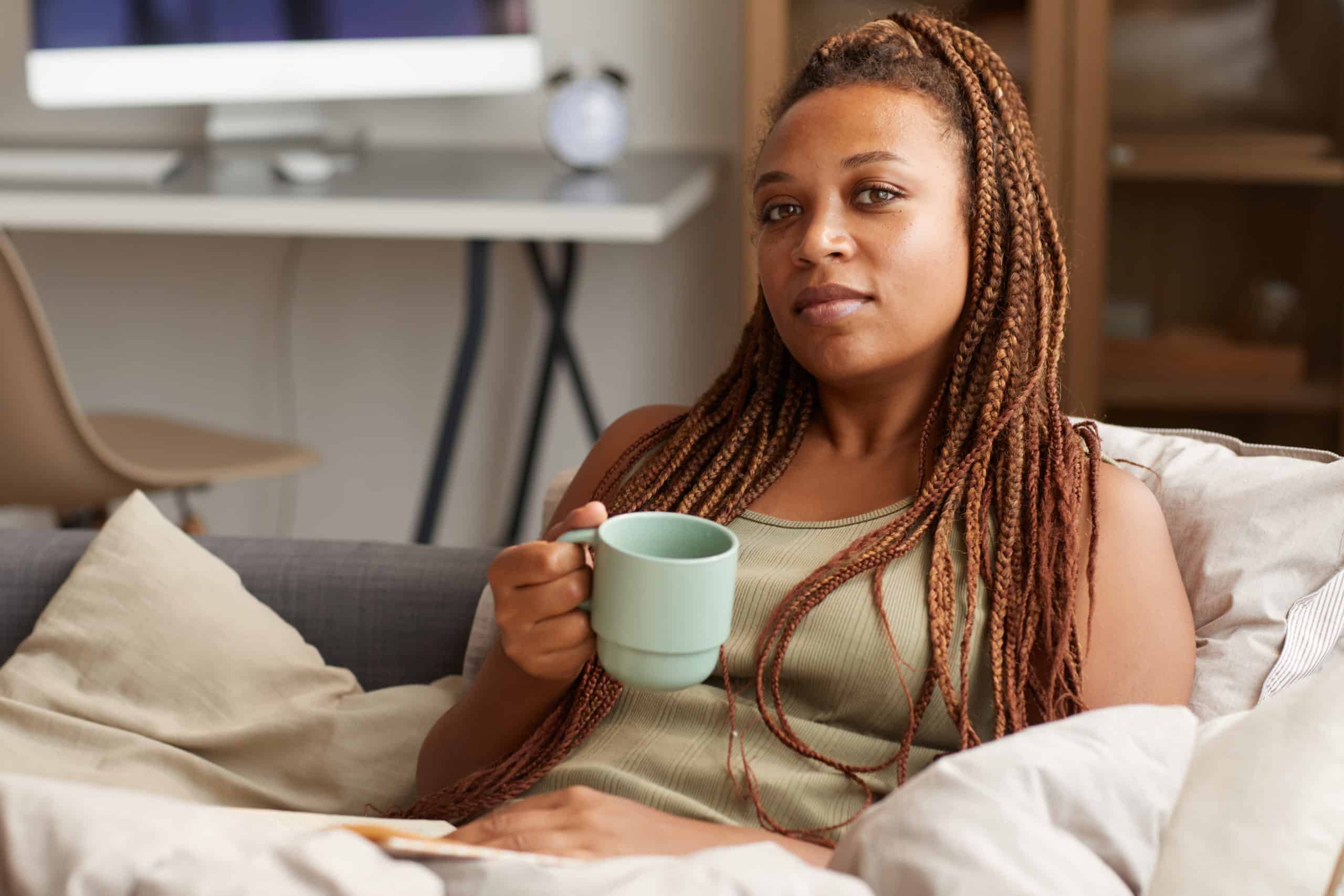 Woman sitting on a couch with a green coffee mug