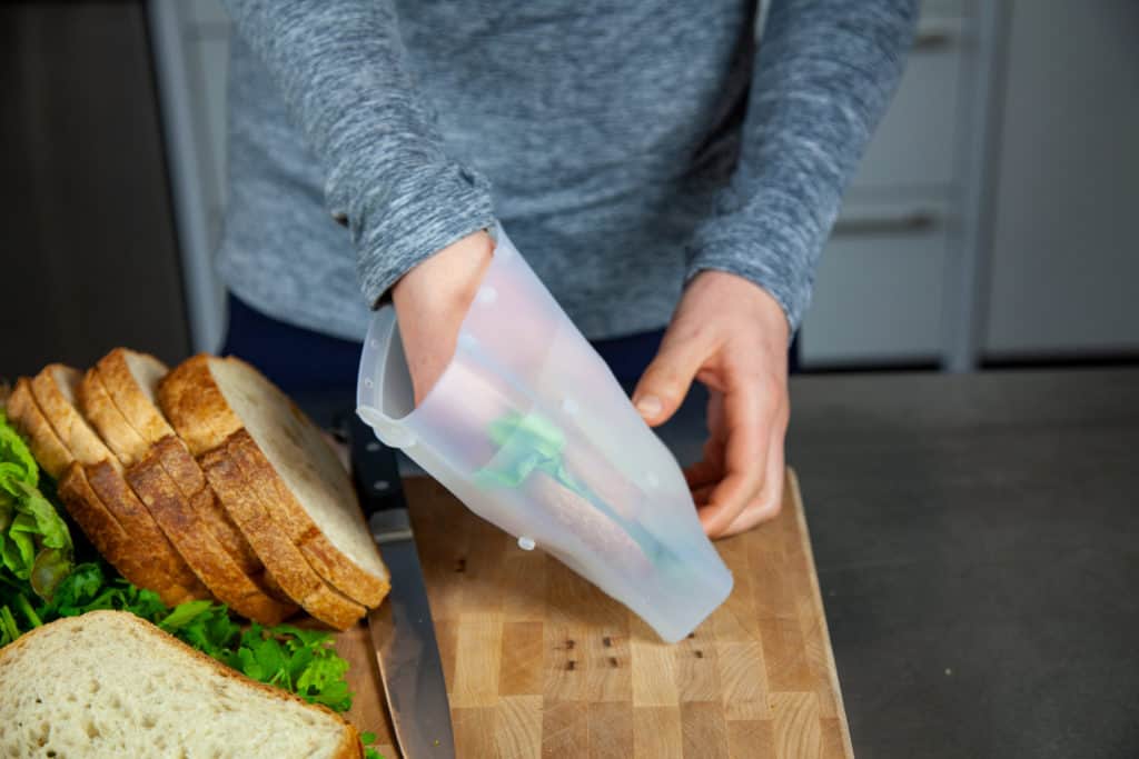 Woman putting a sandwich in a sustainable, reusable food storage bag