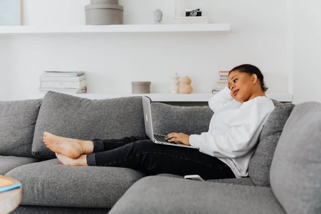 Woman working from her couch with a laptop
