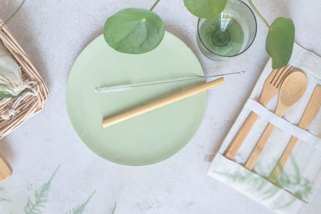 Flatlay of eco-friendly products on a table - bamboo flatware and reusable straw