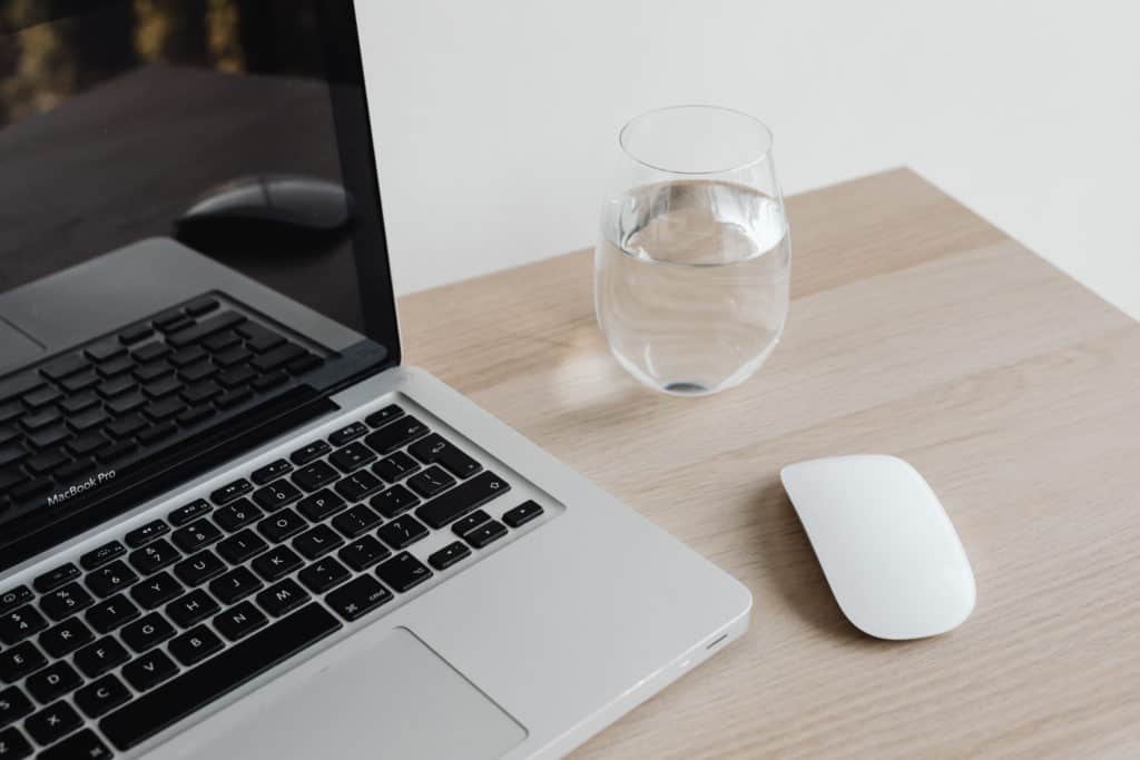 An open laptop and a glass of water on a desk