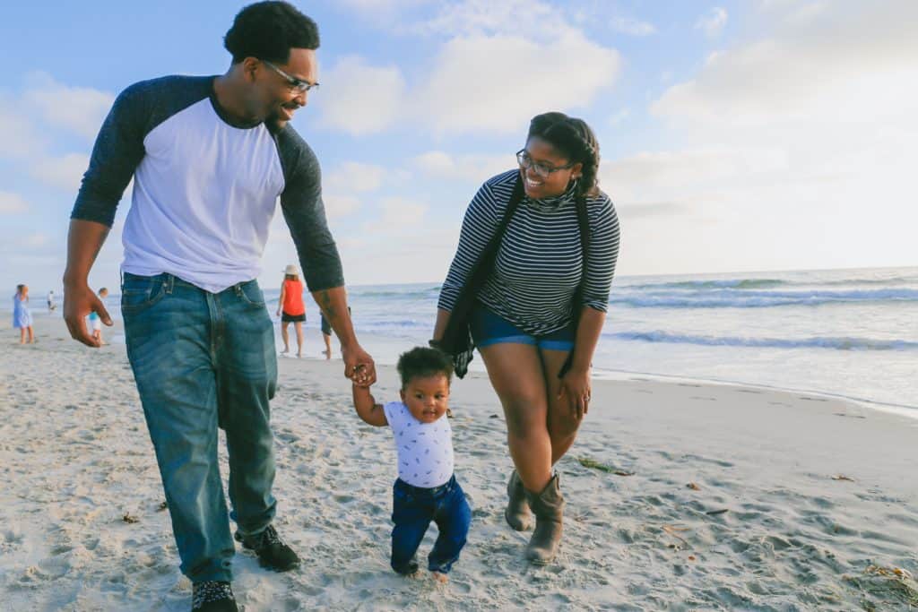 Parents holding hands with a baby on the beach