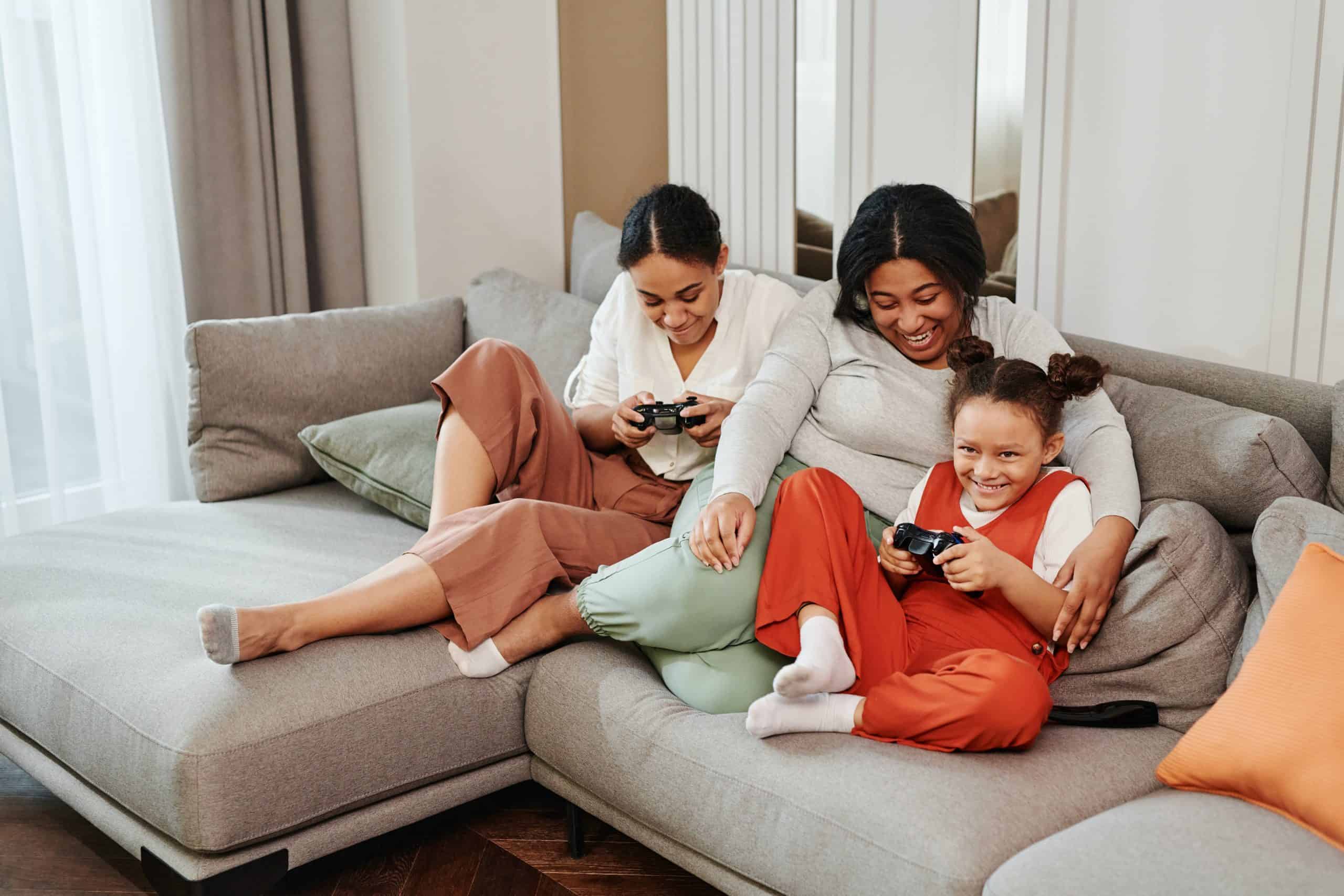 Family of three playing video games on the couch