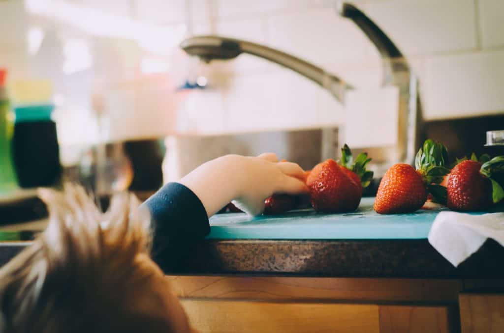 Kid grabbing strawberries off the kitchen counter